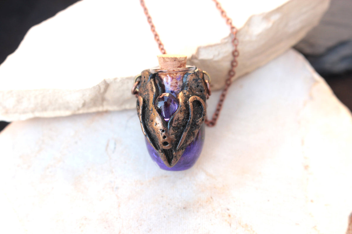 Ancient-inspired fantasy jewelry with bronze ornamentation and a purple vial