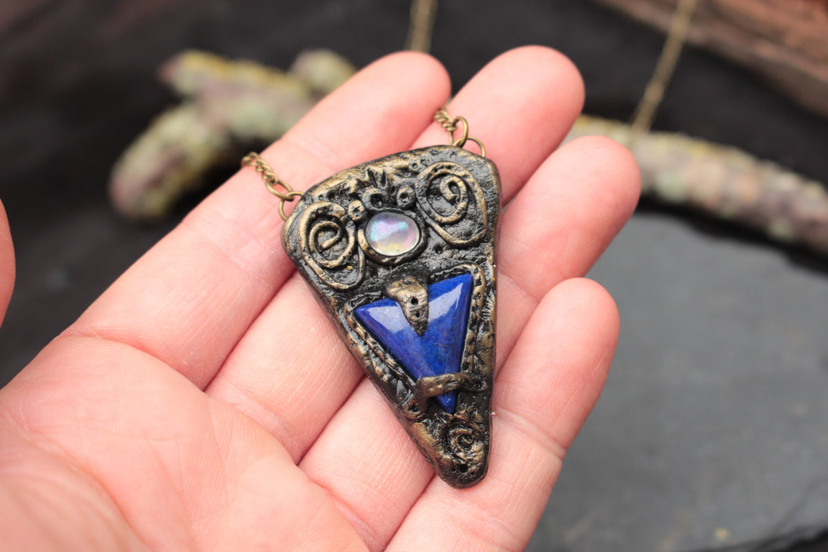 Antique-style fantasy talisman pendant with a mysterious blue stone