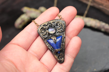 Antique-style fantasy talisman pendant with a mysterious blue stone