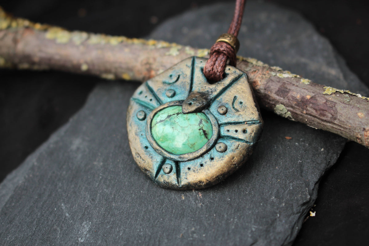 Detailed view of a handmade polymer clay amulet with an aged patina finish