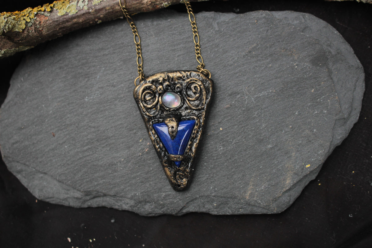 Fantasy pendant featuring a blue gemstone and aged metallic details