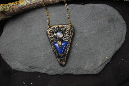 Fantasy pendant featuring a blue gemstone and aged metallic details