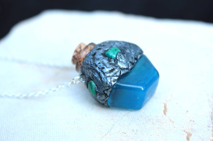 Blue glowing fantasy pendant inspired by a mysterious magical potion