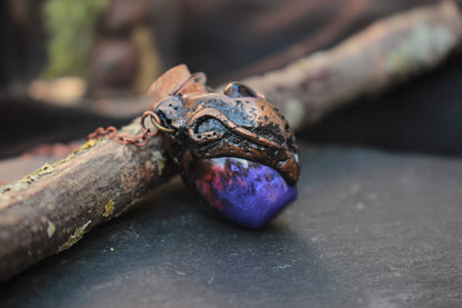 Bronze-toned fantasy pendant with a small purple potion bottle