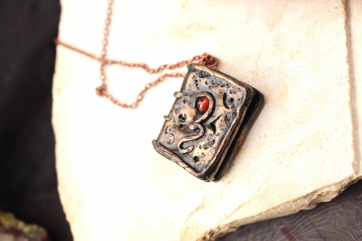 Fantasy spell book pendant featuring a natural carnelian gemstone