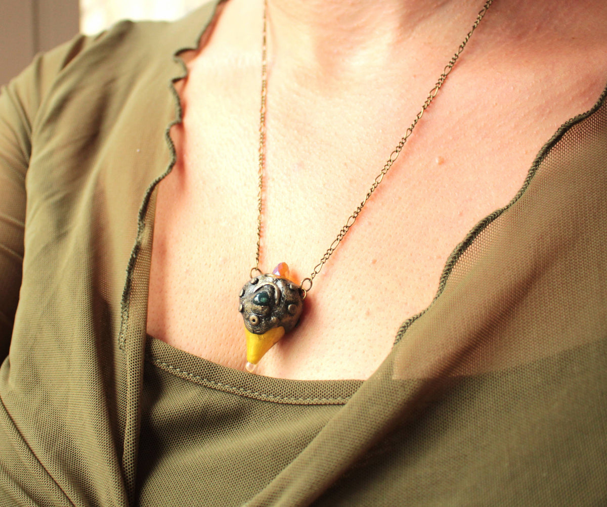 Handmade fantasy necklace featuring a green gemstone, bronze details and a glowing crystal