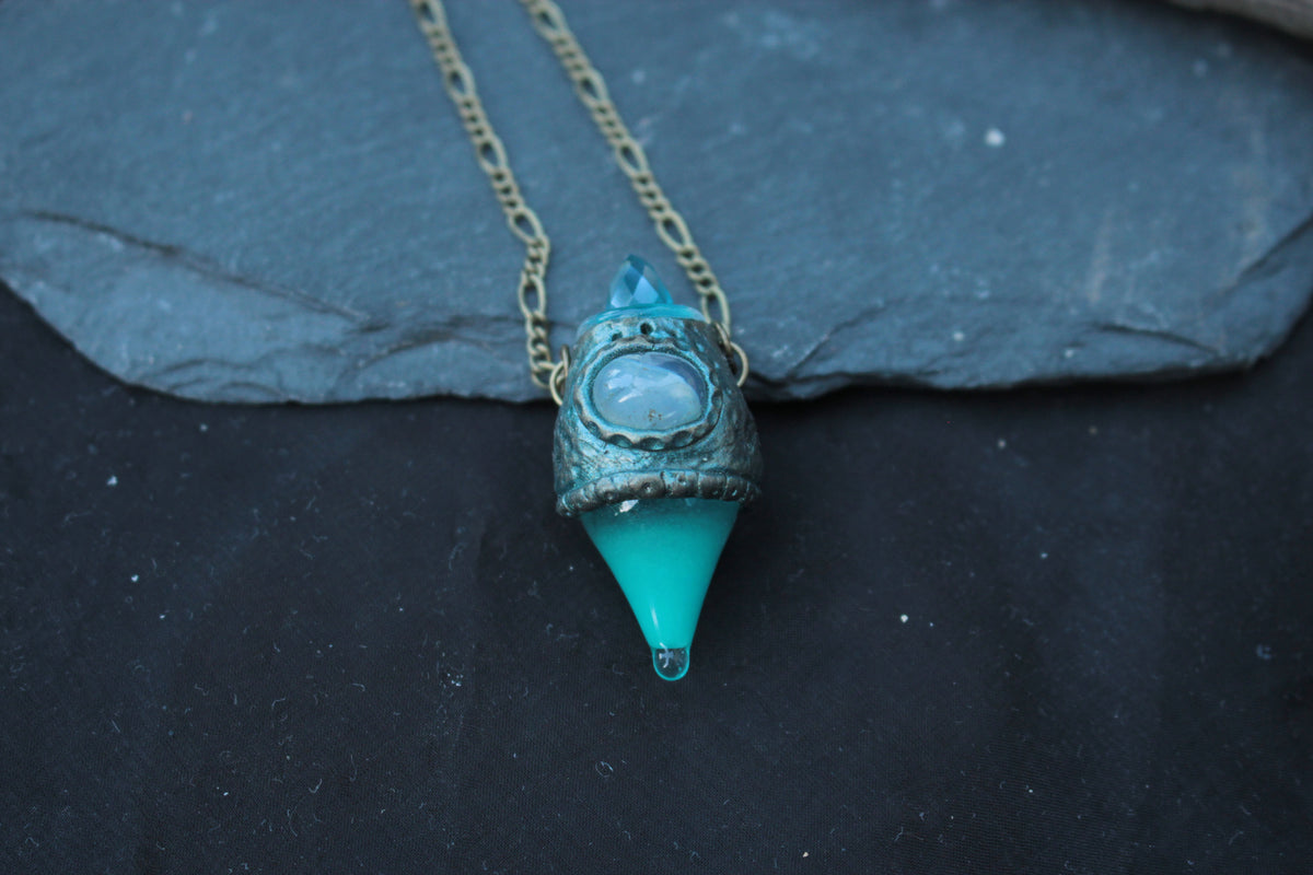 Close-up of a glowing turquoise potion pendant with bronze details