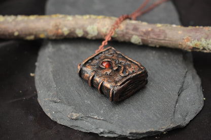 Tiny fantasy book pendant necklace with a red carnelian gemstone