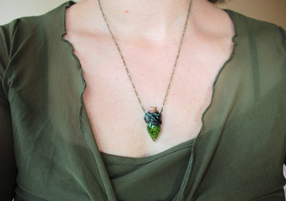 Close-up of the green moss vial and bronze detailing on the pendant