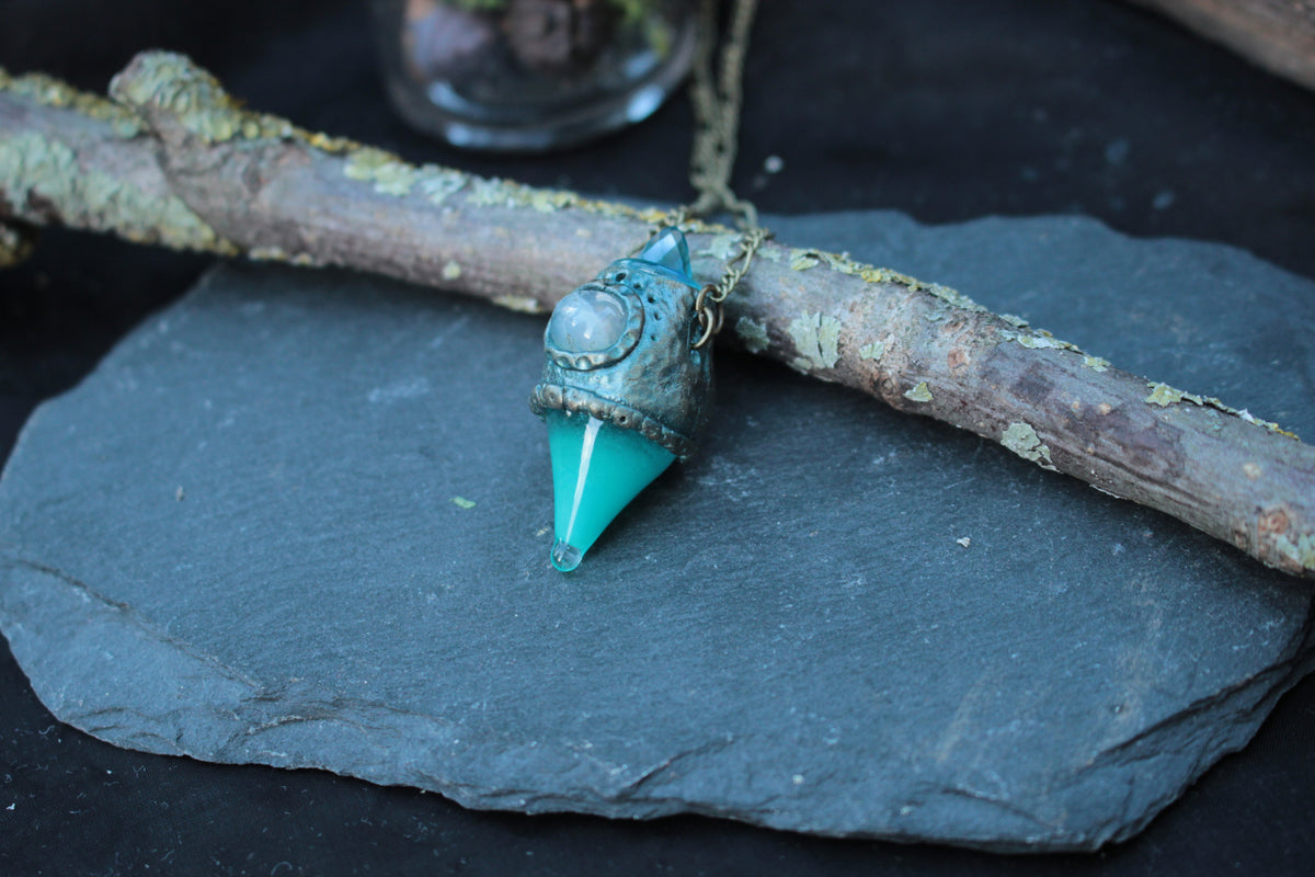 Handmade fantasy potion bottle necklace with a glowing turquoise crystal