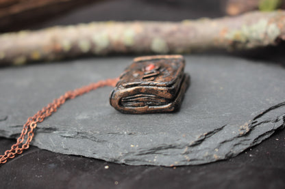Small handmade spell book pendant necklace with a rustic metallic finish