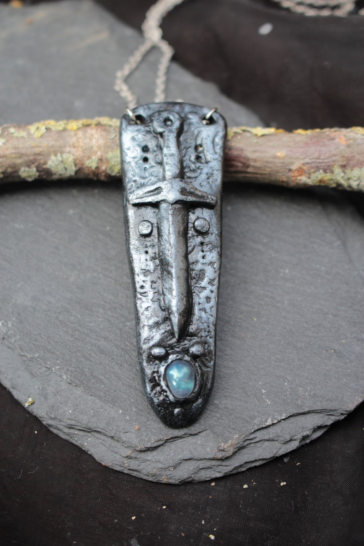 Close-up of a handmade polymer clay sword necklace