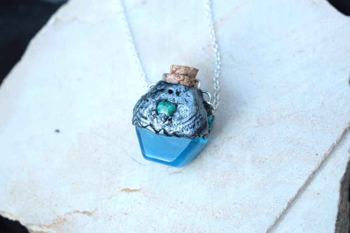 Fantasy vial necklace featuring a glowing blue potion and bronze decoration