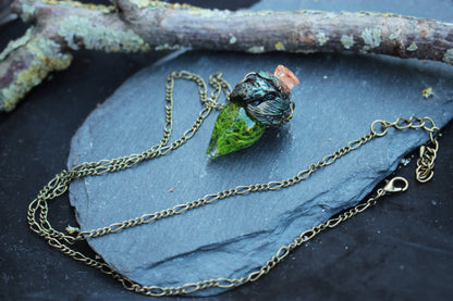 Forest-inspired pendant with green moss and sculpted bronze details