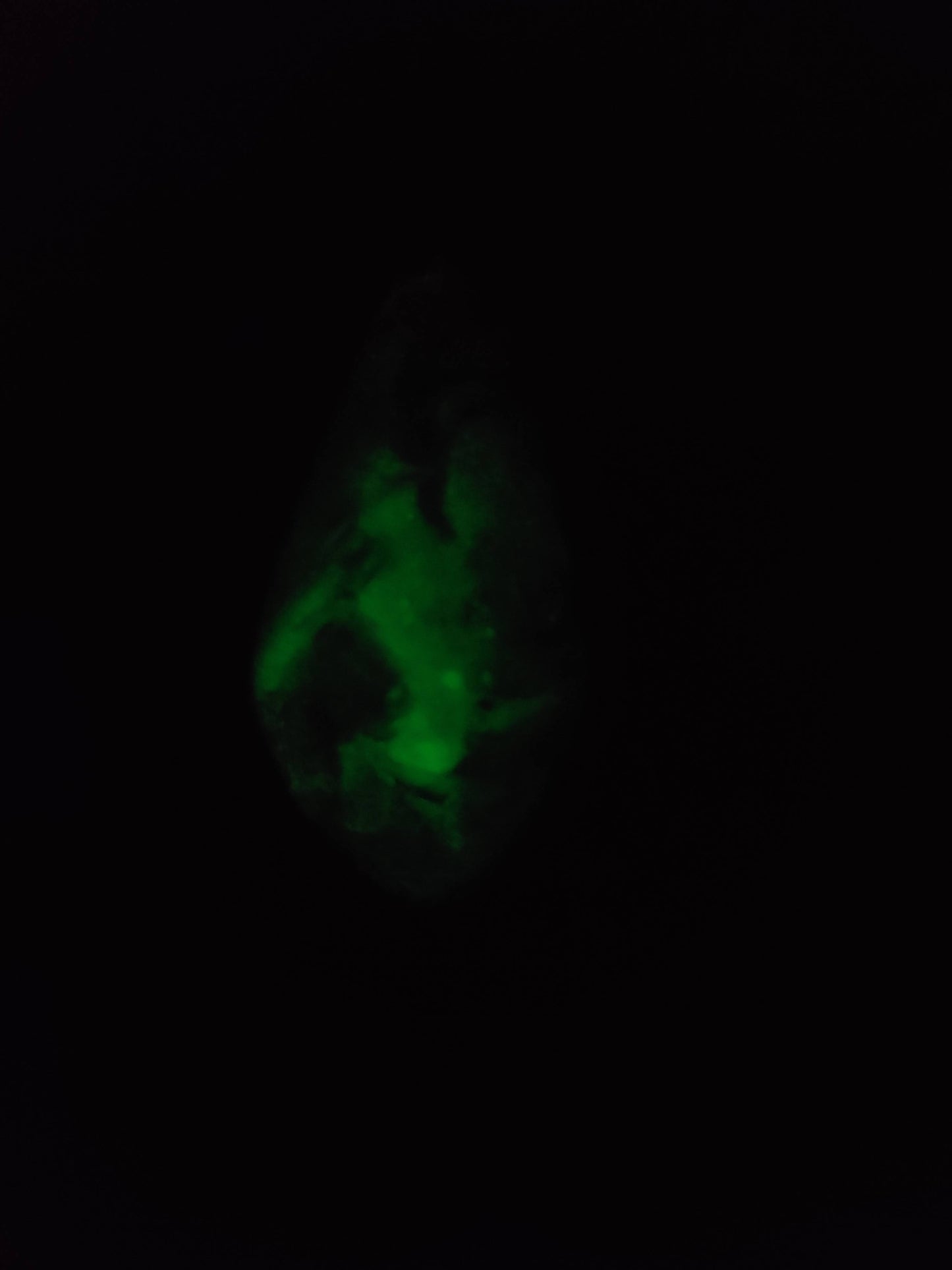 Glow-in-the-dark resin crystal glowing green on the wooden treasure chest