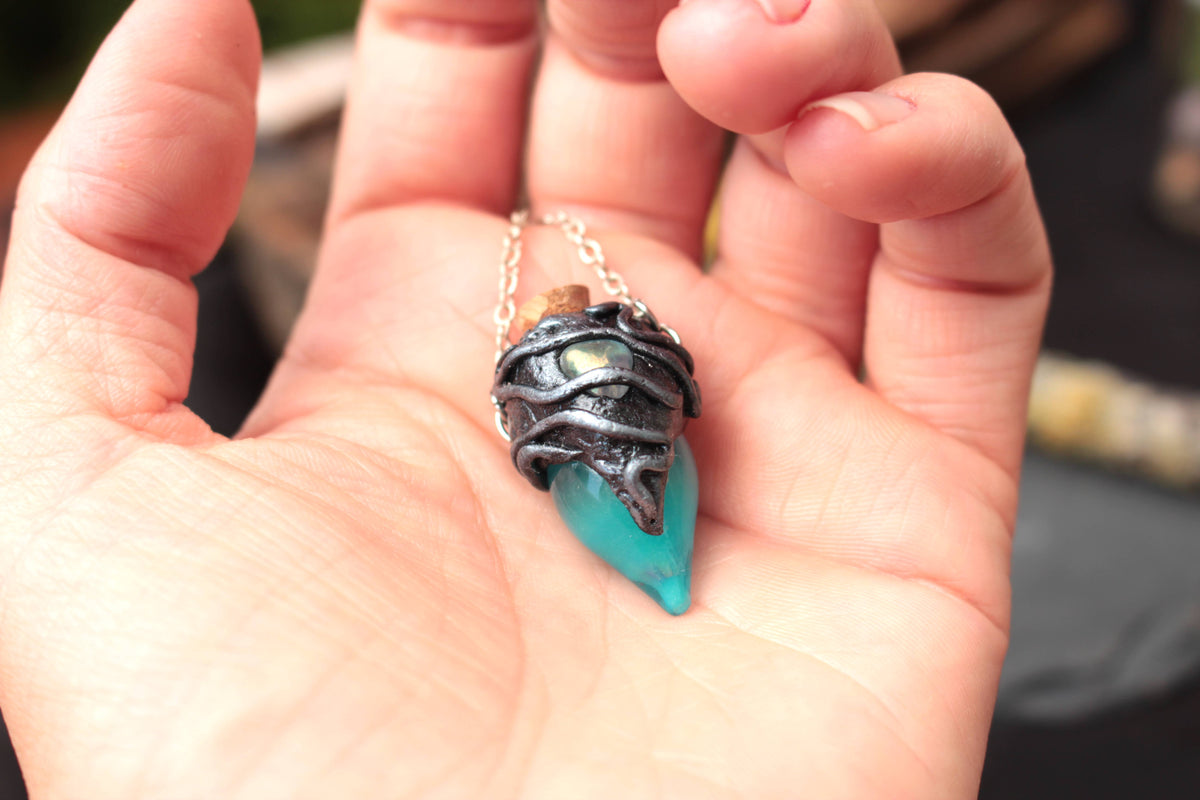 Turquoise potion pendant glowing green in the dark