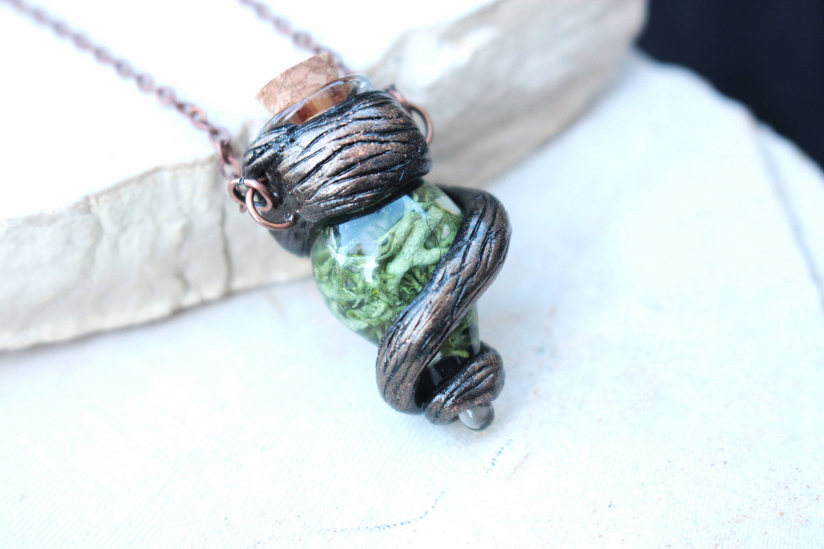 Handmade forest-inspired necklace with a small green vial and rustic botanical details