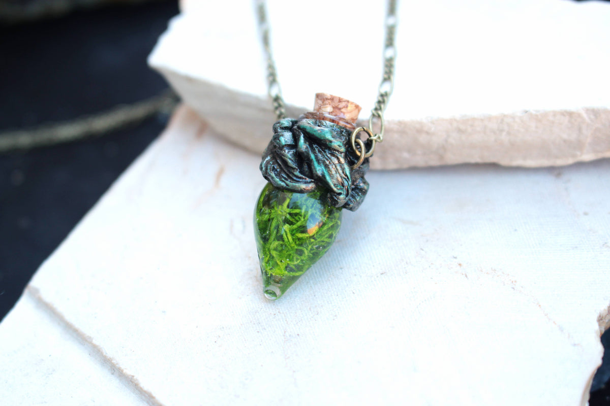 Green glass vial pendant with moss and an antique bronze setting