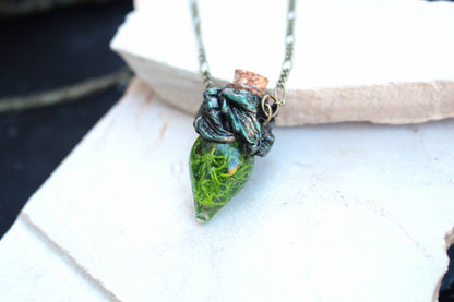 Green glass vial pendant with moss and an antique bronze setting