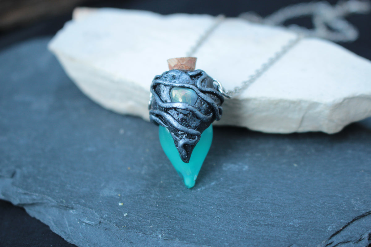 Glowing turquoise potion bottle necklace shown in the dark