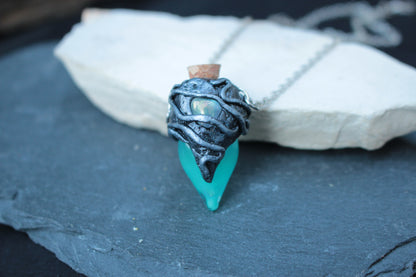 Glowing turquoise potion bottle necklace shown in the dark