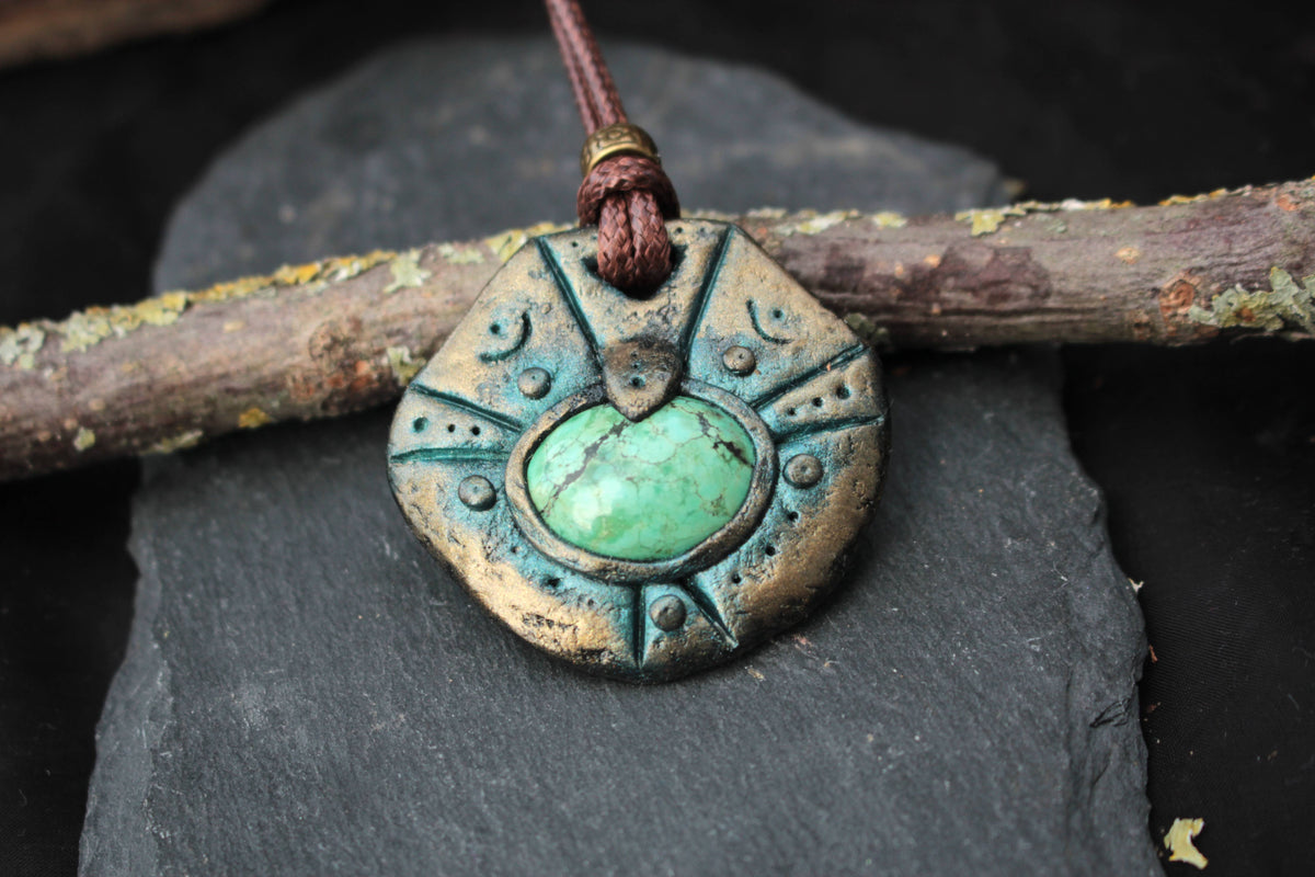 Close-up of an ancient relic inspired pendant with a green stone centerpiece