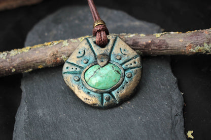 Close-up of an ancient relic inspired pendant with a green stone centerpiece