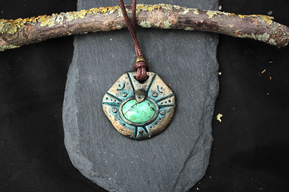 Handmade polymer clay relic pendant with weathered details and a green stone