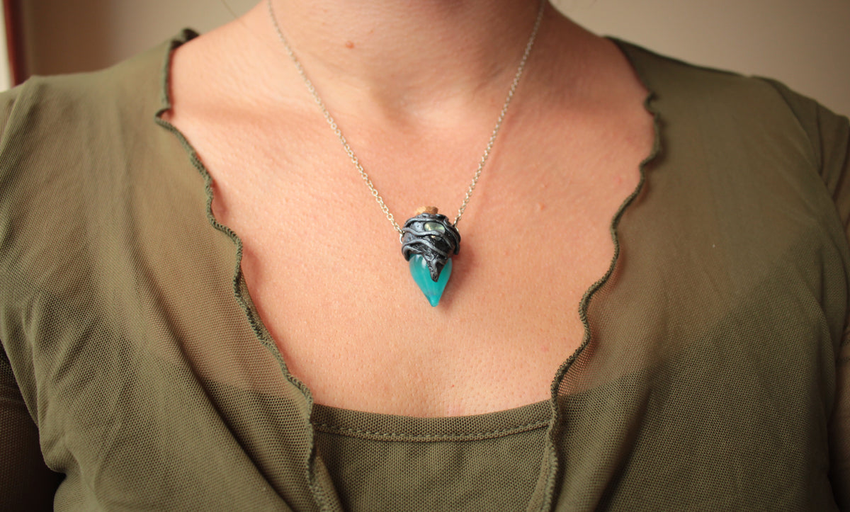Small handmade potion bottle pendant with turquoise liquid and mystical green glow