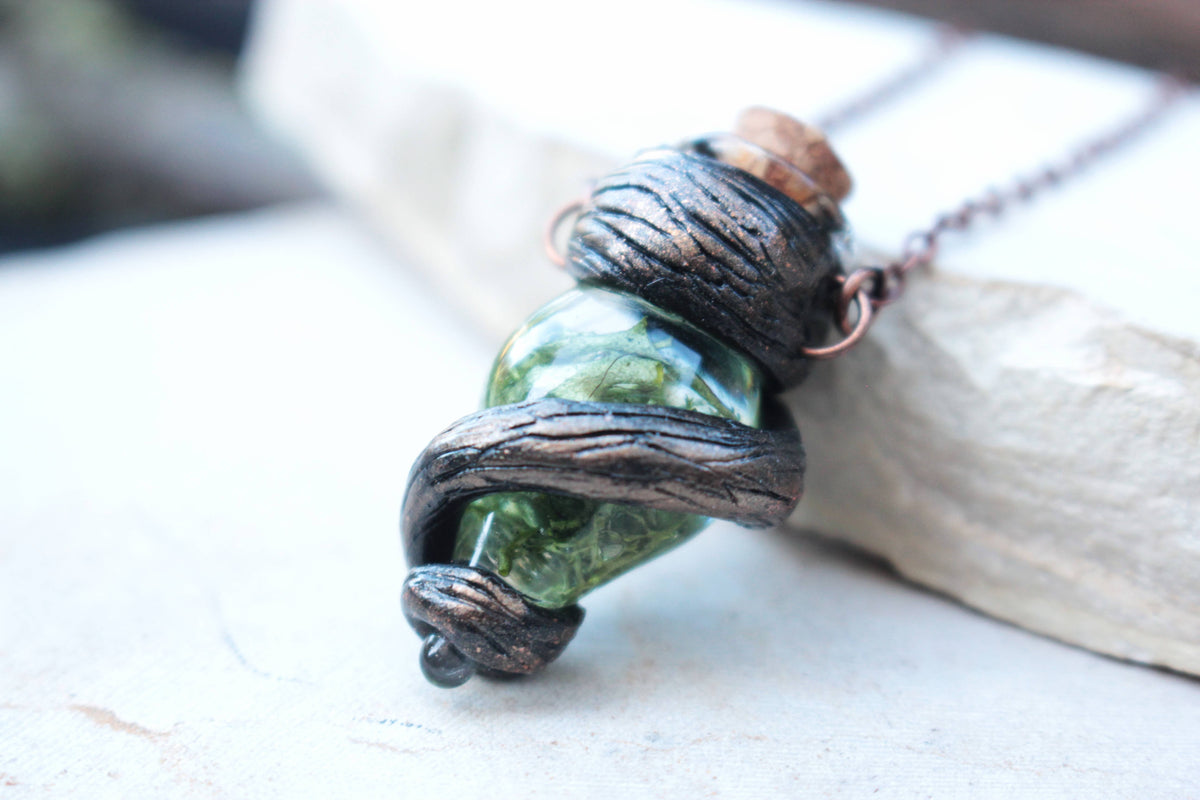 Fantasy vial pendant featuring deep green tones, twisted branches and an antique finish