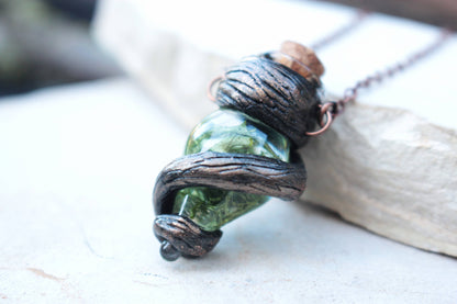Fantasy vial pendant featuring deep green tones, twisted branches and an antique finish