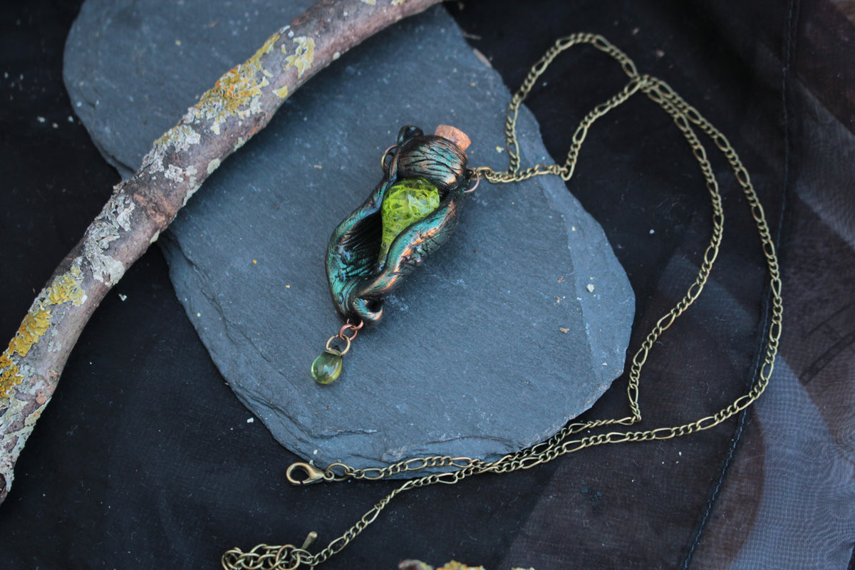 Magical green pendant necklace with botanical details and mystical forest aesthetic