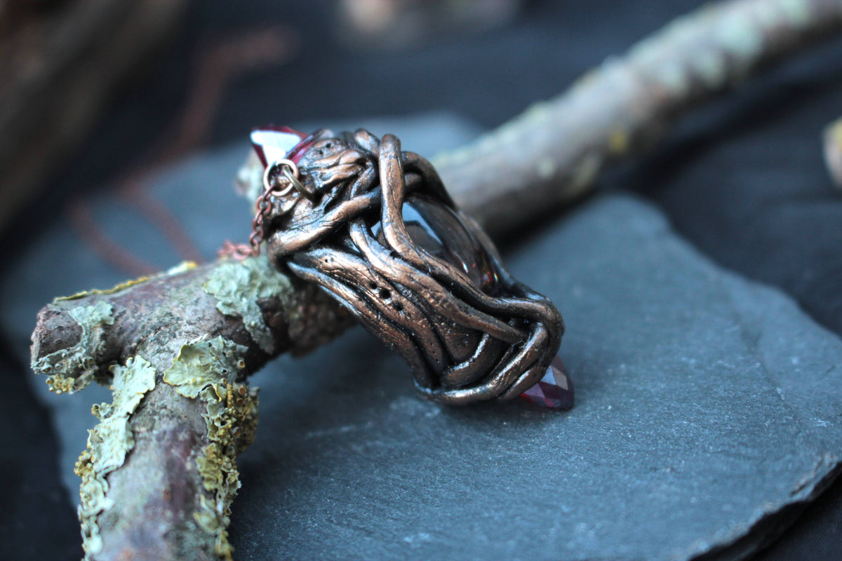 Handmade fantasy amulet featuring glowing-looking red crystals and a mystical design