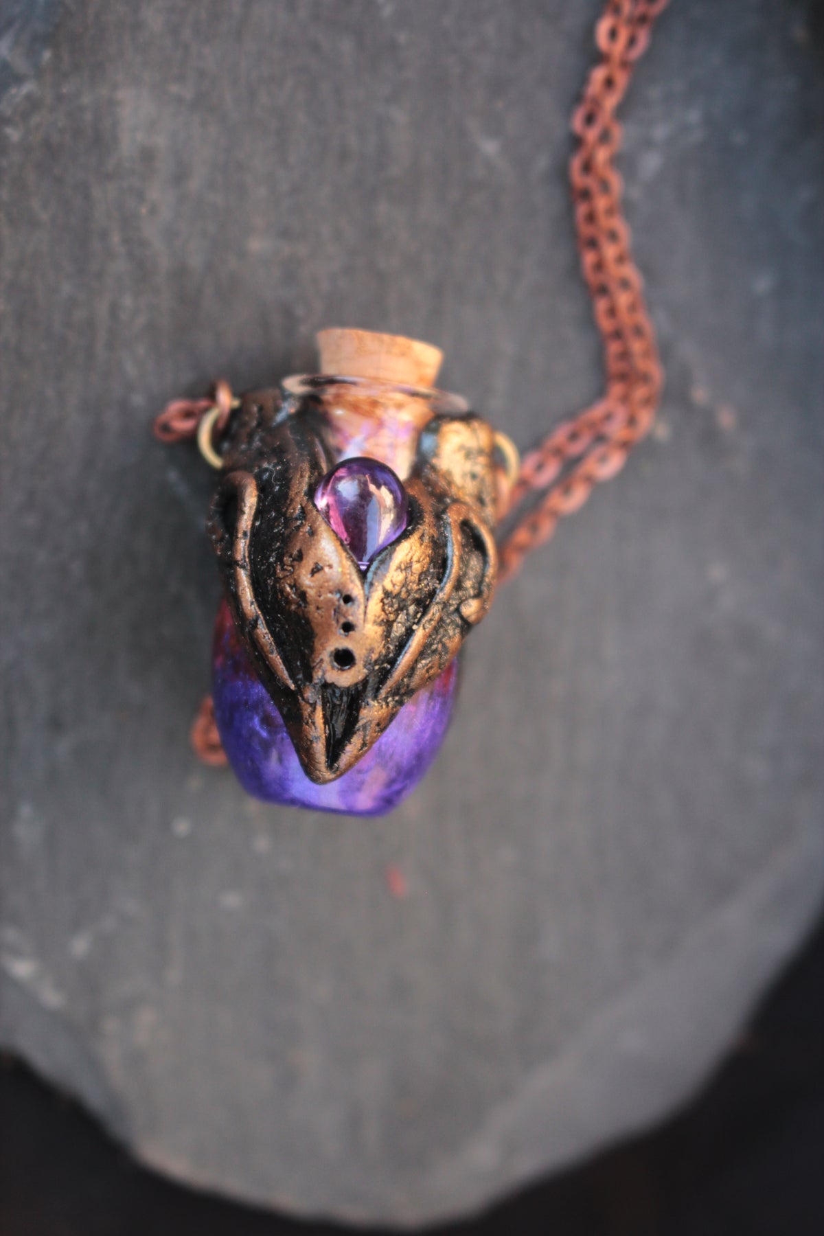 Magical handmade amulet featuring a violet potion bottle suspended from a metal chain