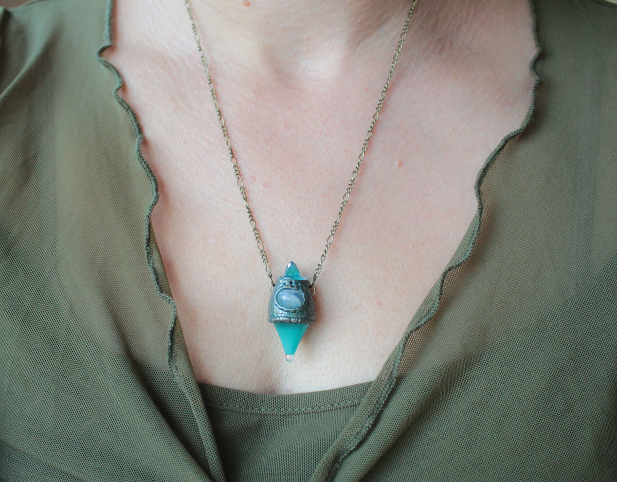 Mystical forest-inspired necklace with a glowing turquoise potion pendant