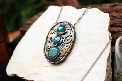 Fantasy rune amulet with weathered metallic finish and green gemstone details