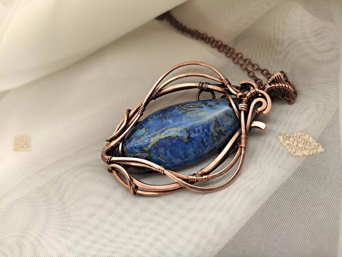 lose up of blue crazy agate gemstone wrapped in polished copper wire