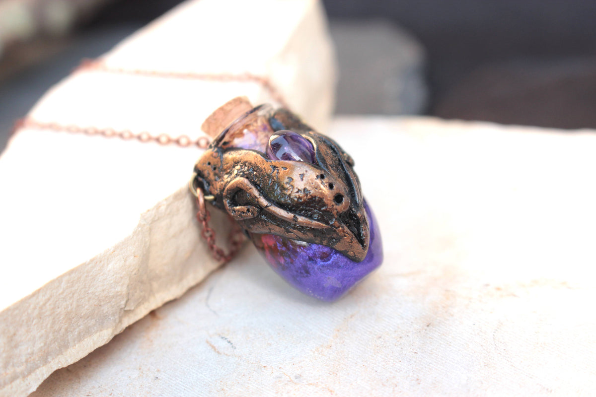Ornate handmade necklace with a violet glass potion bottle and bronze finish