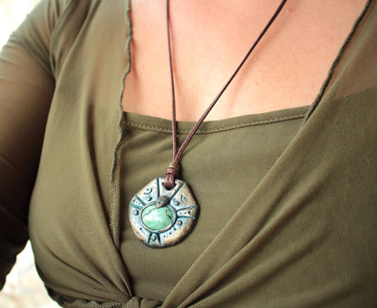 Antique patina amulet hanging from a long brown waxed cotton cord