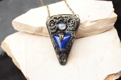 Detailed handmade Lost Talisman pendant with a deep blue central stone