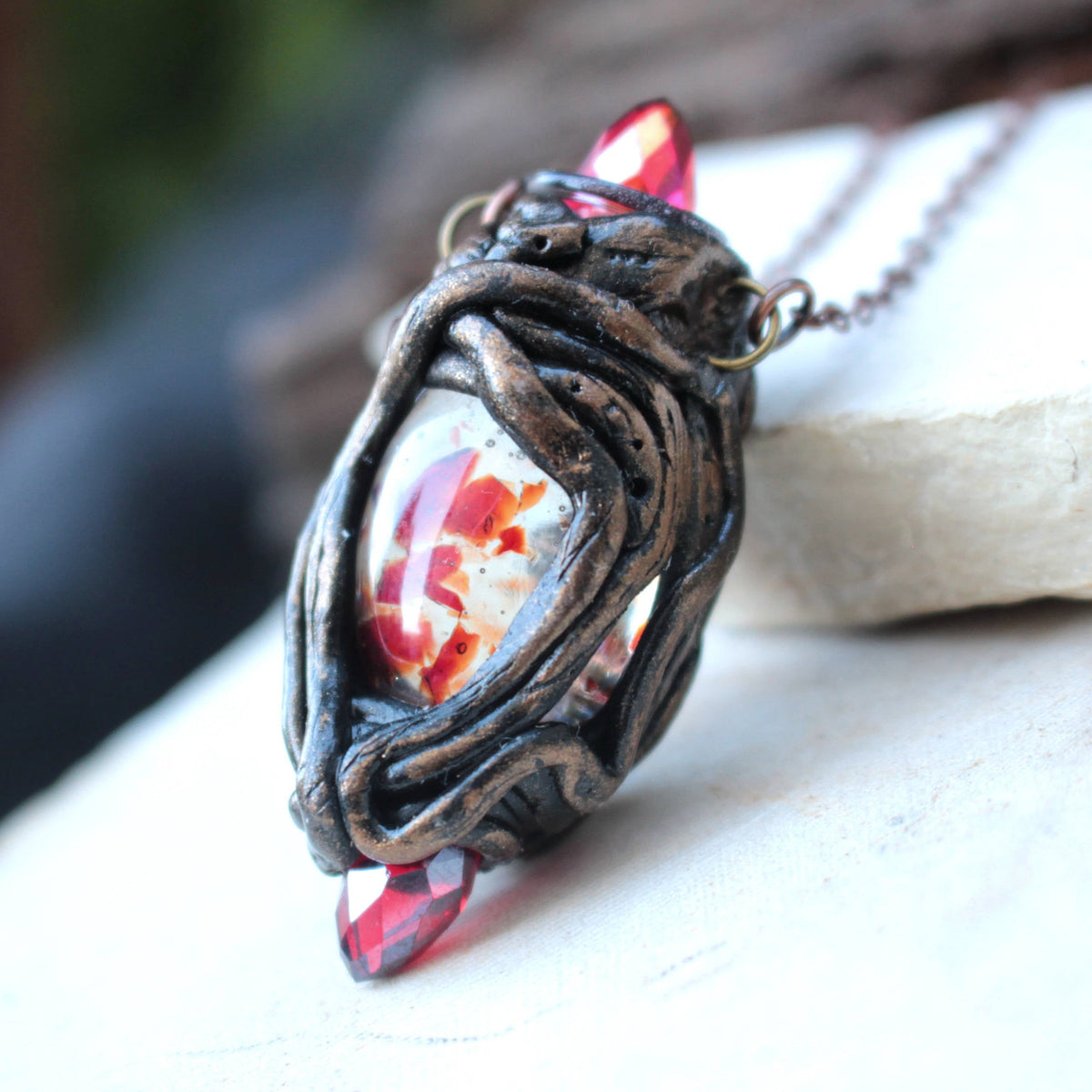 Handmade fantasy necklace featuring three red crystals and a broken crystal held between two whole crystals