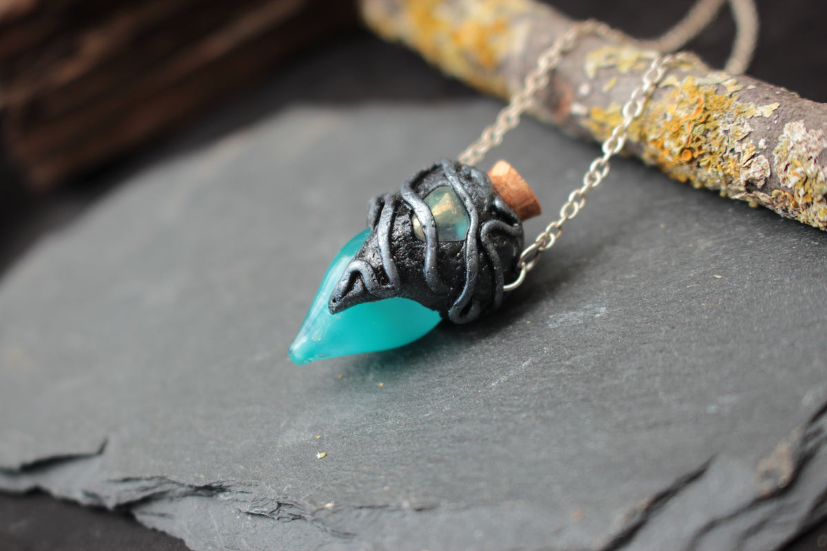 Detail of turquoise glowing vial and gemstone on handmade necklace