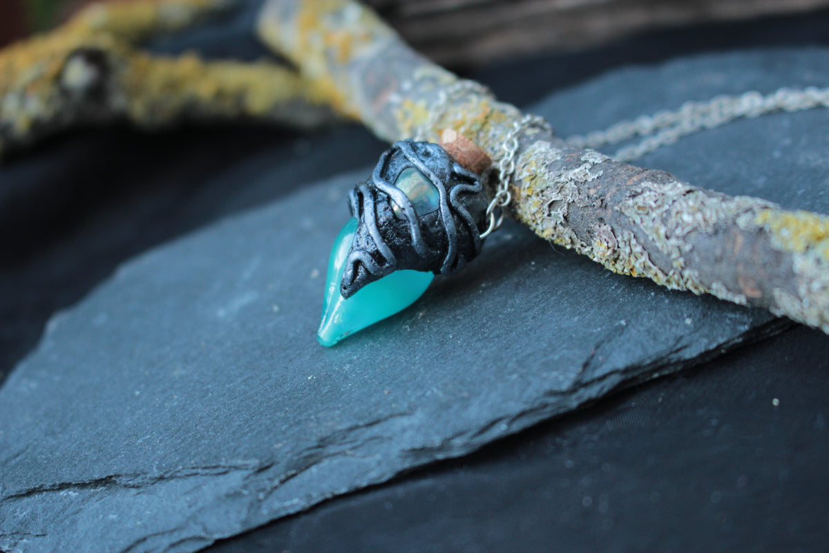 Close-up of a turquoise glass potion bottle pendant with gemstone