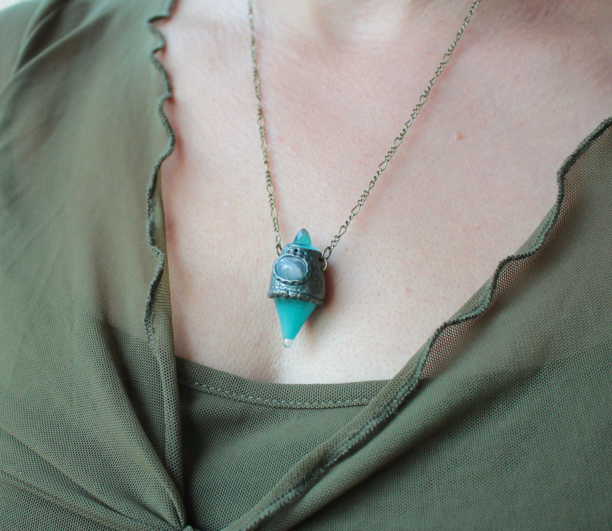Turquoise potion jewelry with a glowing miniature bottle and fantasy-inspired design