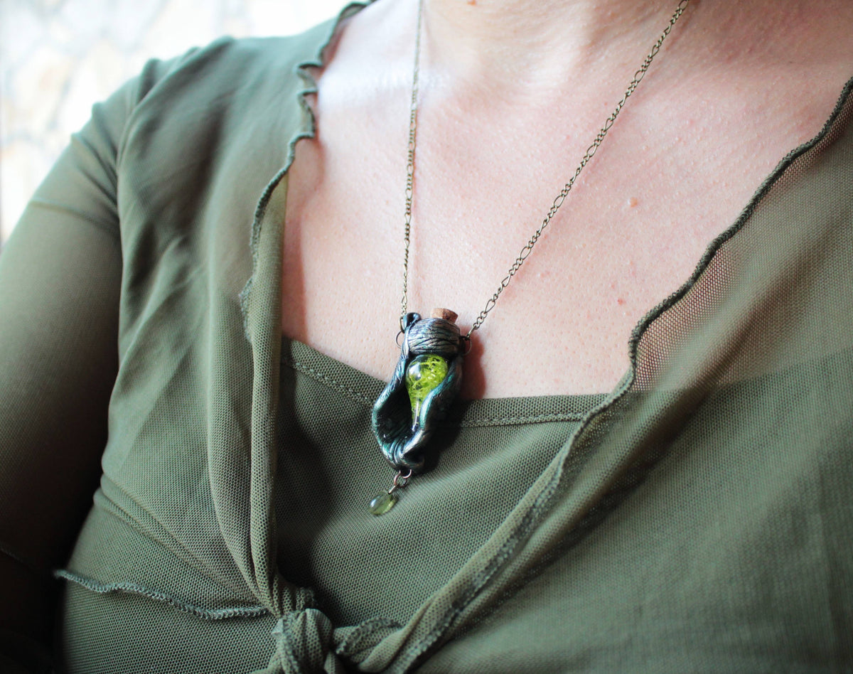 Whimsical forest jewelry featuring a mystical green vial pendant and botanical elements